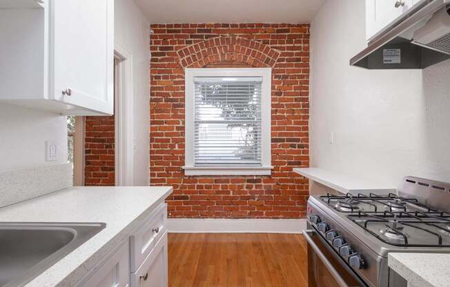 A kitchen with a brick wall and a stove top oven at Westmore Manor Apartments, Los Angeles, CA