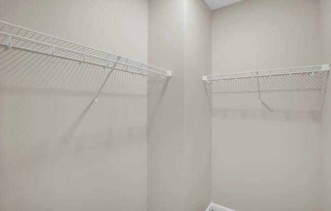a walk in closet with white walls and a mirrored closet door
