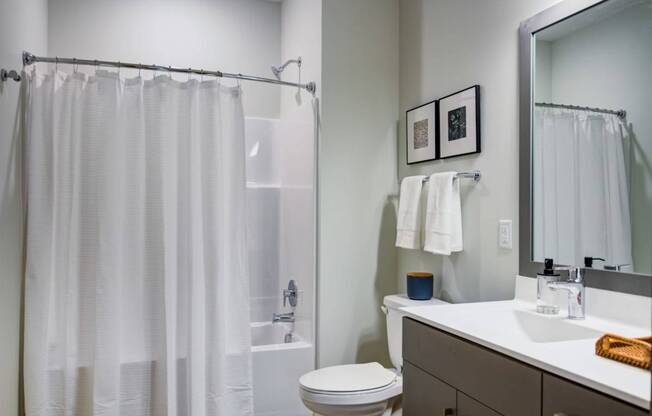 A white bathroom with a toilet, sink, and shower curtain.