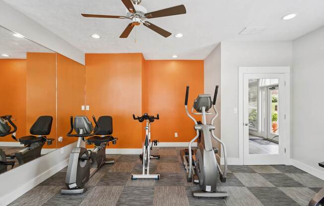 A gym with orange walls and a variety of exercise equipment.