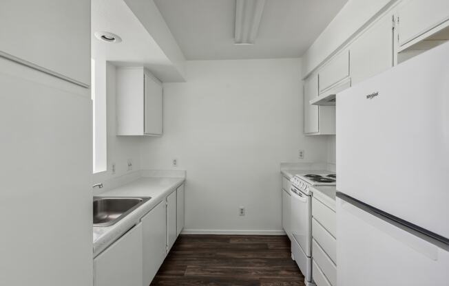 a kitchen with white cabinets and white appliances and a stainless steel sink