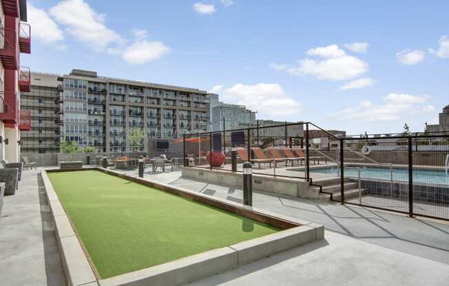 a green astroturf soccer field on a rooftop patio with a pool in the background