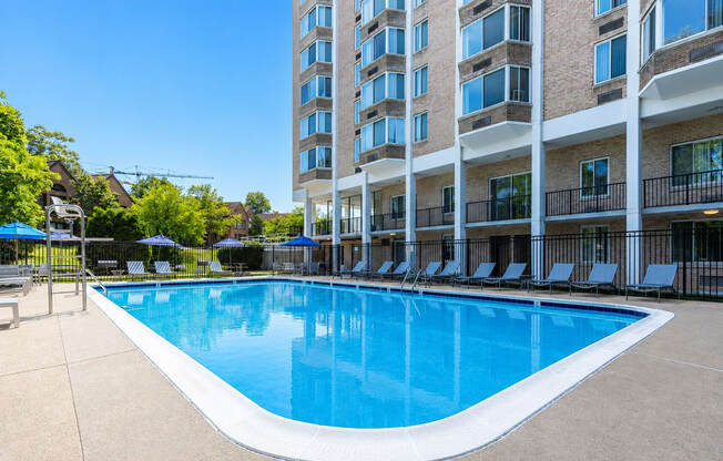A large swimming pool in front of a multi-story apartment building.