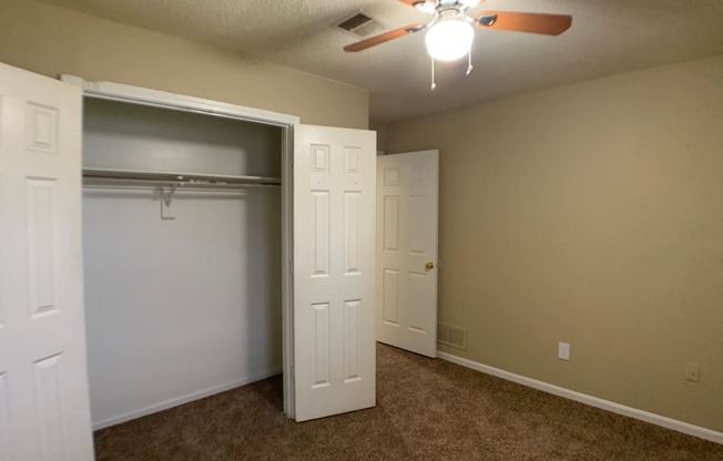 large carpeted bedroom with closet and ceiling fan