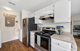 A kitchen with a stove, refrigerator, and cabinets.