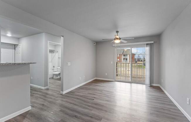 A spacious room with a sliding glass door leading to a balcony.