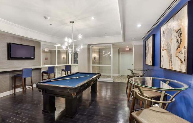 A room with a pool table and chairs.