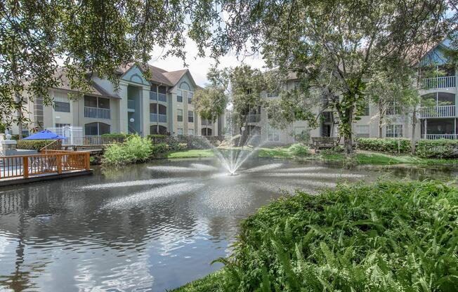 a tree in front of a house surrounded by water