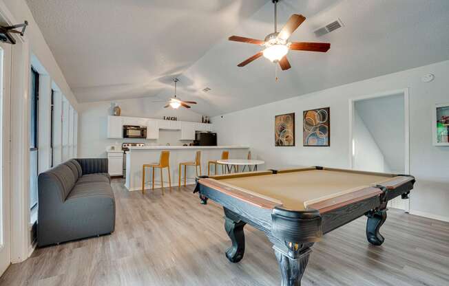 a living room with a pool table and a kitchen with a bar