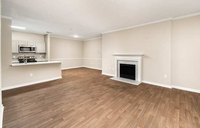 an empty living room with a fireplace and a kitchen