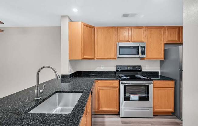 A kitchen with a black granite countertop and wooden cabinets.