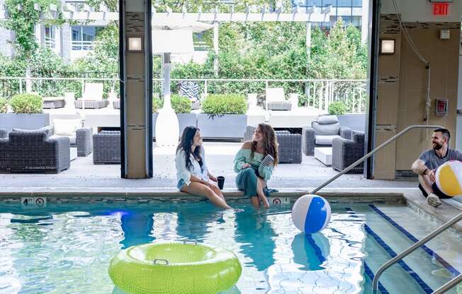 a man and two women sitting by the pool with a beach ball