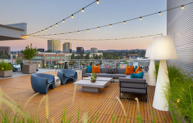 a roof deck with couches and chairs and a city in the background