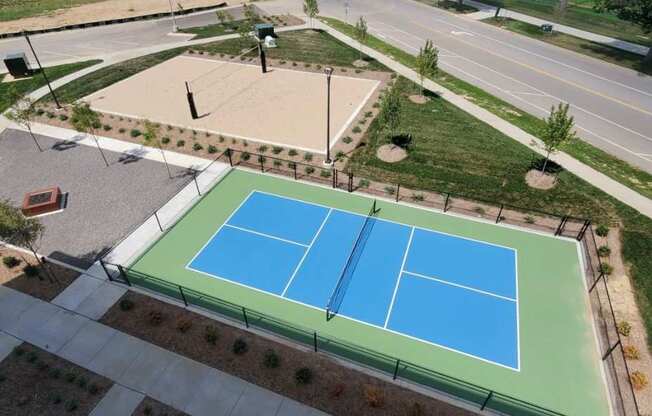 A tennis court is surrounded by a green fence.