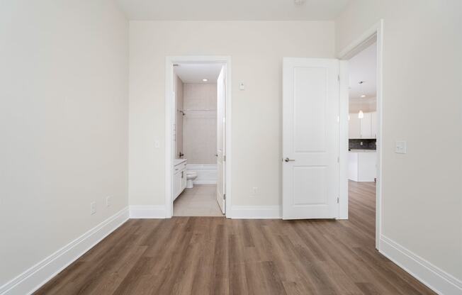 a bedroom with white walls and hardwood floors