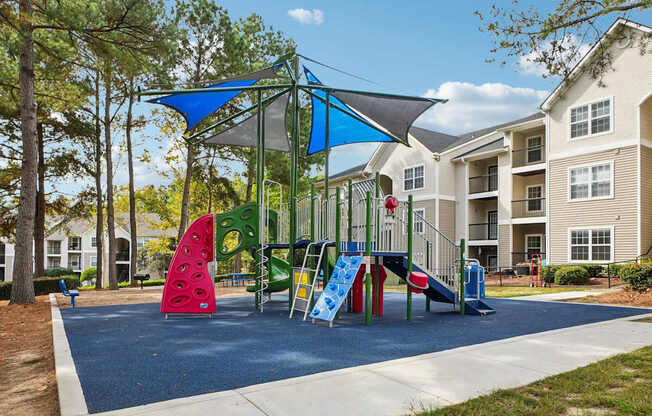 A playground with a blue shade structure and a slide.