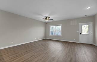 an empty living room with wood floors and a ceiling fan