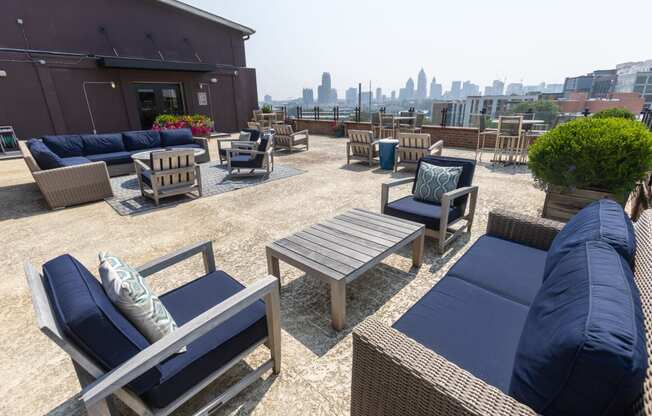 an outdoor patio with blue couches and wooden chairs with a view of the philadelphia skyline