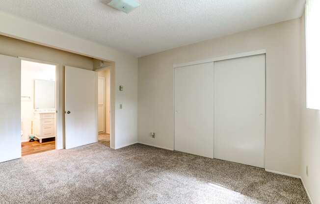 an empty bedroom with white closets and a carpeted floor