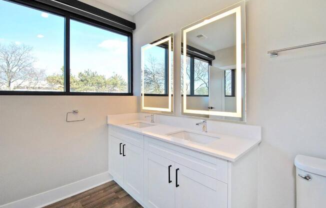 A white bathroom with a large window and a white sink.