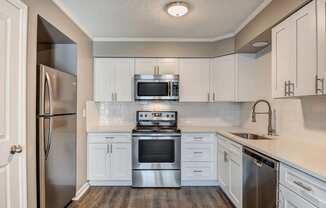 Image of a kitchen with a breakfast bar, refrigerator, sink, and oven.