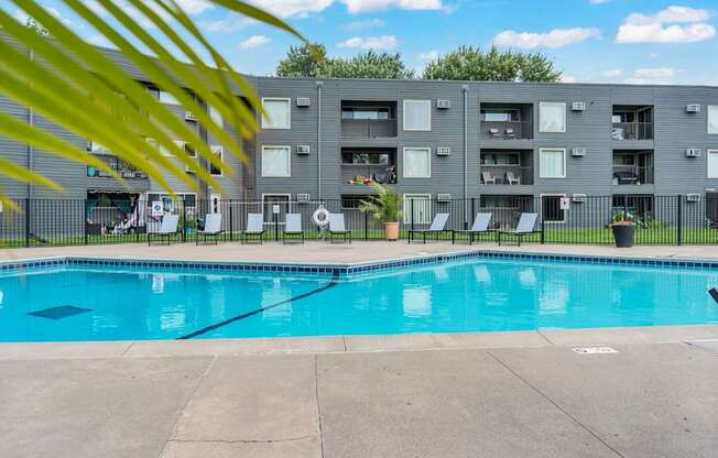 A swimming pool in front of a grey apartment building.