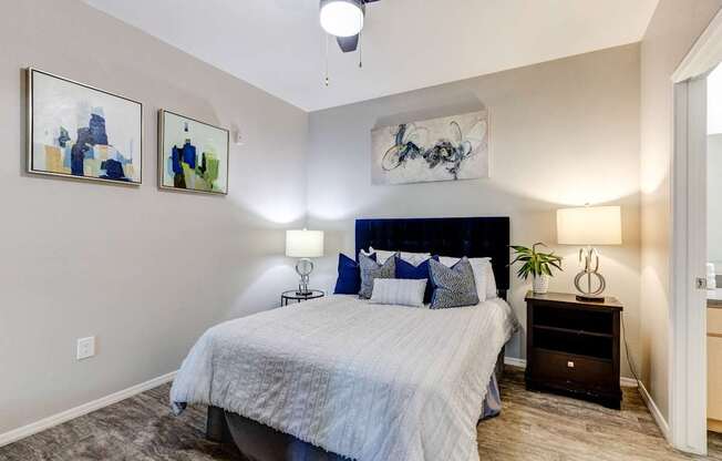 A bedroom with a bed, nightstand, and two wall art pieces.