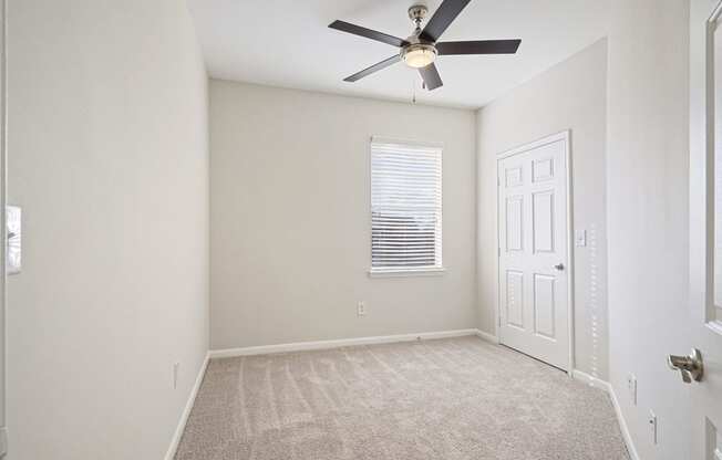 an empty room with a ceiling fan and a white door