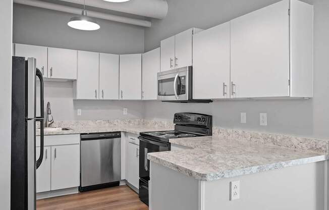 A kitchen with white cabinets and a marble countertop.