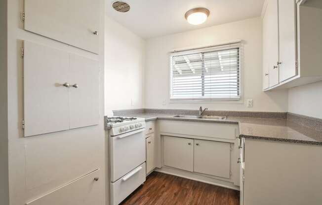 Kitchen with white gas stove, granite countertops, White kitchen cabinets