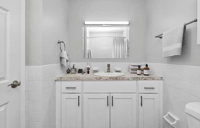 Model Bathroom with White Cabinets and Wood-Style Flooring at Stone Ends Apartments in Stoughton, MA.