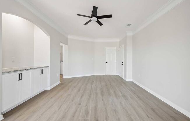 A spacious room with a ceiling fan and light wood flooring.