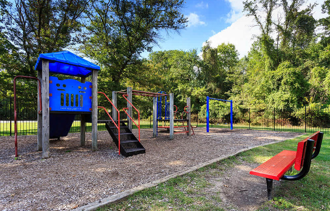 A playground with a blue shelter, red slide, and a red bench.