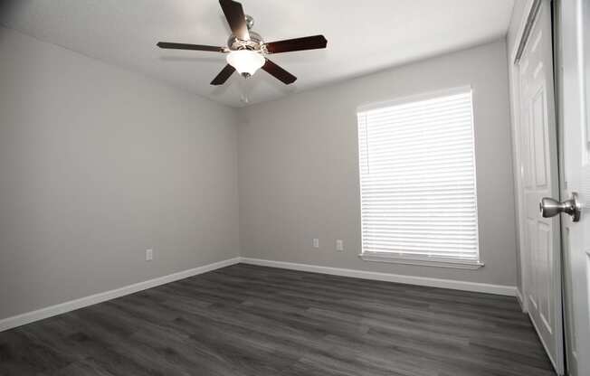 an empty room with a ceiling fan and a window