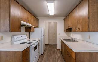 an empty kitchen with white appliances and wooden cabinets. Fargo, ND Windsor Apartments