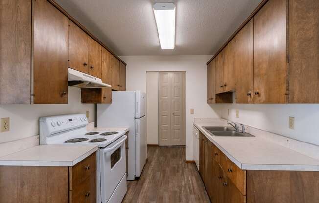 an empty kitchen with white appliances and wooden cabinets. Fargo, ND Windsor Apartments