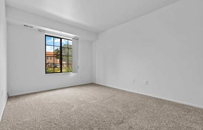 a bedroom with white walls and a window