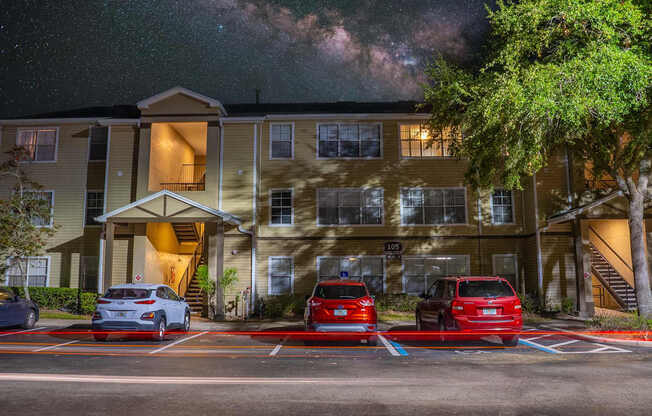 A building with a parking lot in front of it at night.