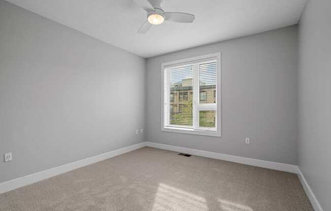 an empty room with a window and a ceiling fan