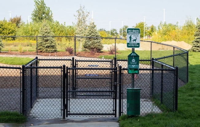 A sign on a post in front of a fence indicates a pet waste area.