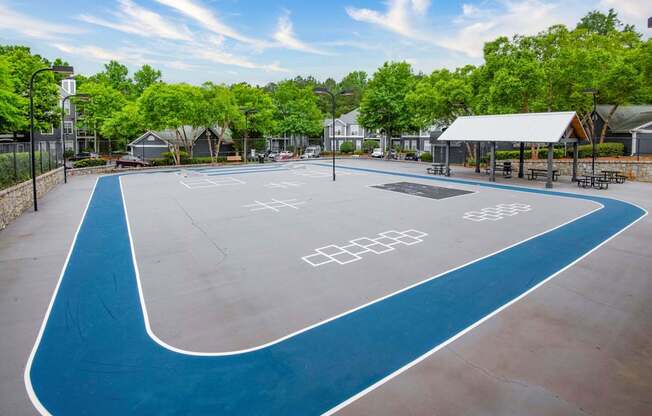 A blue and white painted basketball court in a park.