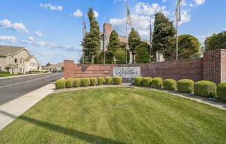 A brick wall with a sign that says "Oakland" in front of a grassy area.