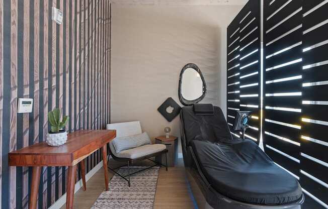 a treatment room with a black chair and a mirror