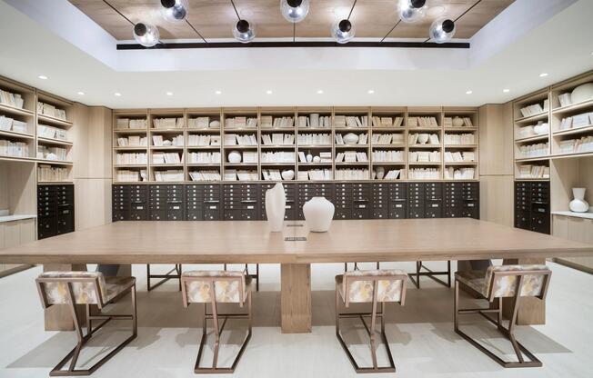 A dual-purpose mailroom and workspace featuring a communal table, custom shelving, and an organized setting for daily routines and focused tasks.