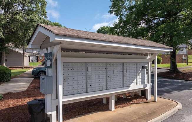A white wooden bench with a white roof is in front of a building.