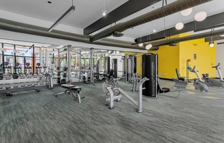 a gym with weights and cardio equipment in a building with yellow walls