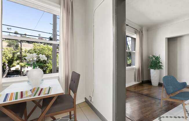 a small dining room with a small table and two chairs in front of a large window at Del Mor Apartments, California, 90026