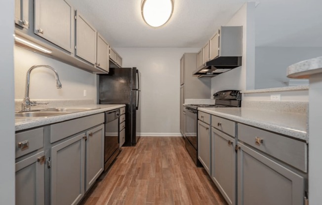 A kitchen with wooden floors and grey cabinets.