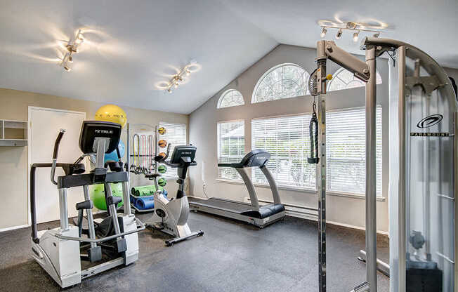 A home gym with a treadmill, elliptical trainer, and a stationary bike.