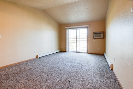 an empty living room with a window and carpet